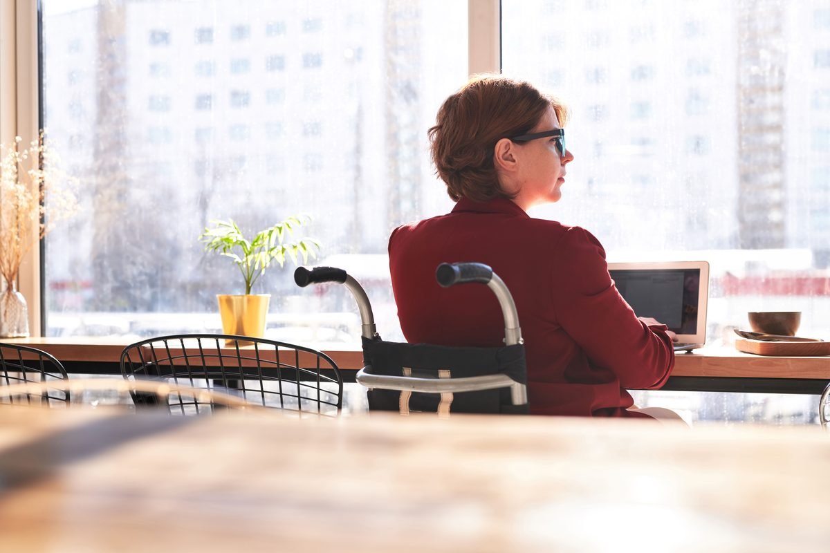 Person using a laptop at a cafe workspace by a window.