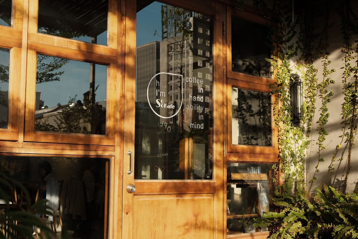 Warm sunlight filtering through the glass doorway of a quiet coffee shop.