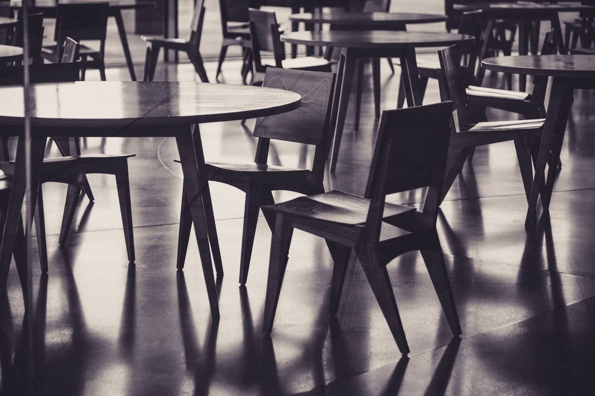 Empty wooden tables and chairs inside a cafe setting.