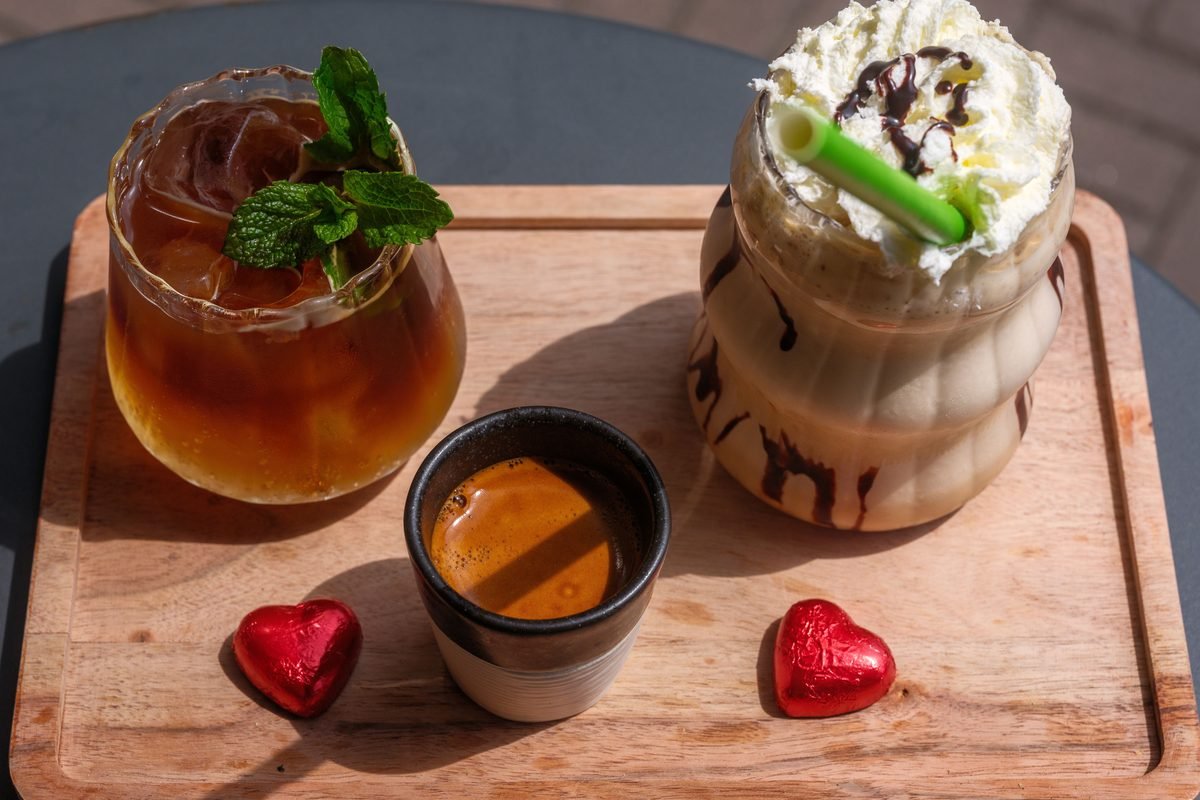 A vibrant display of iced drinks and espresso on a wooden tray.