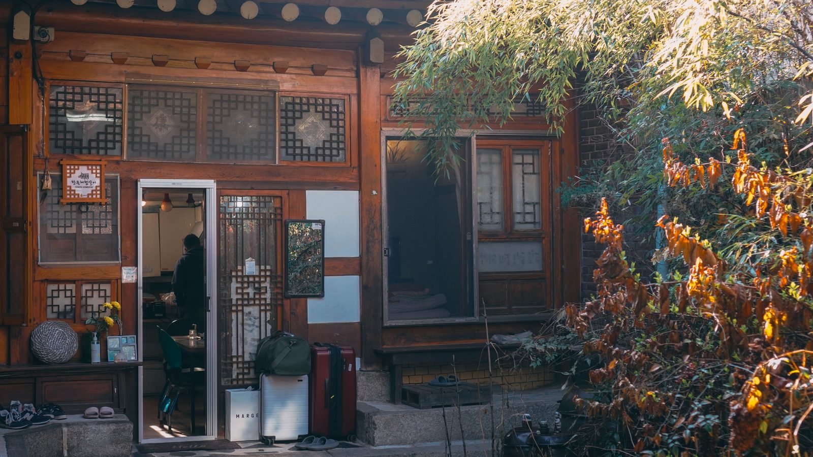 Traditional Seoul hanok featuring a wooden facade beside lush plants.