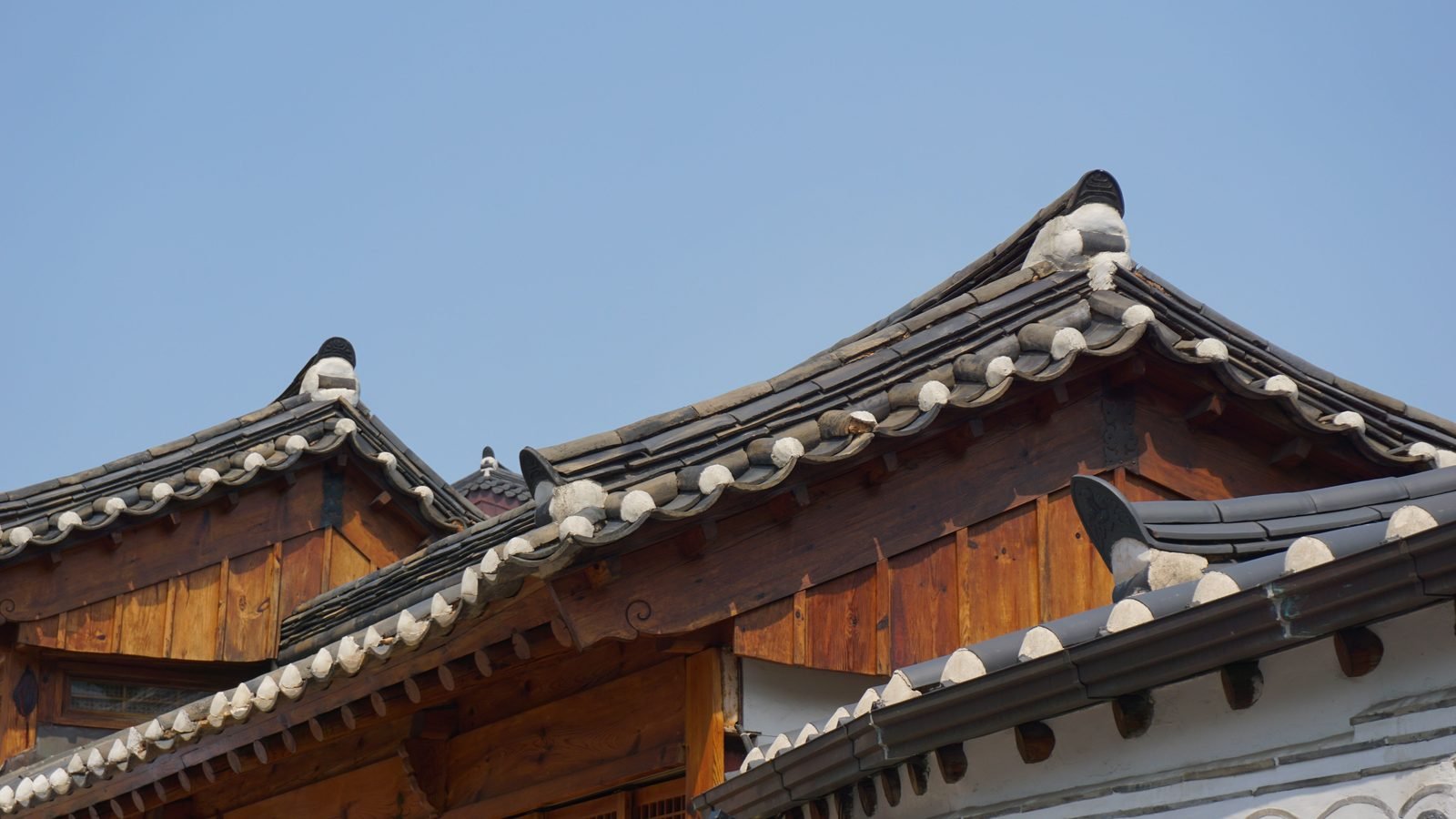 Traditional Korean Hanok roofs under a clear blue sky.