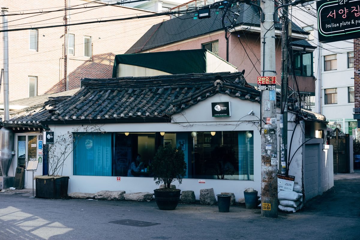 Traditional café with tiled roof in a Seoul street setting.