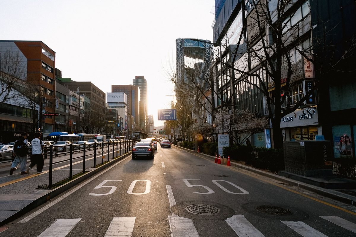Vibrant urban street scene in Seoul at sunset with cars and modern architecture.