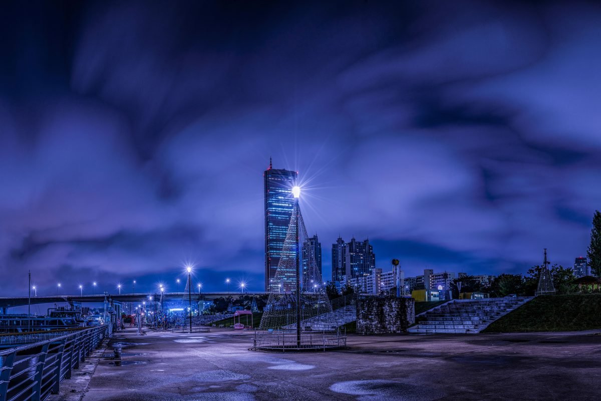 Night view of Seoul skyline with dramatic clouds and lighting.