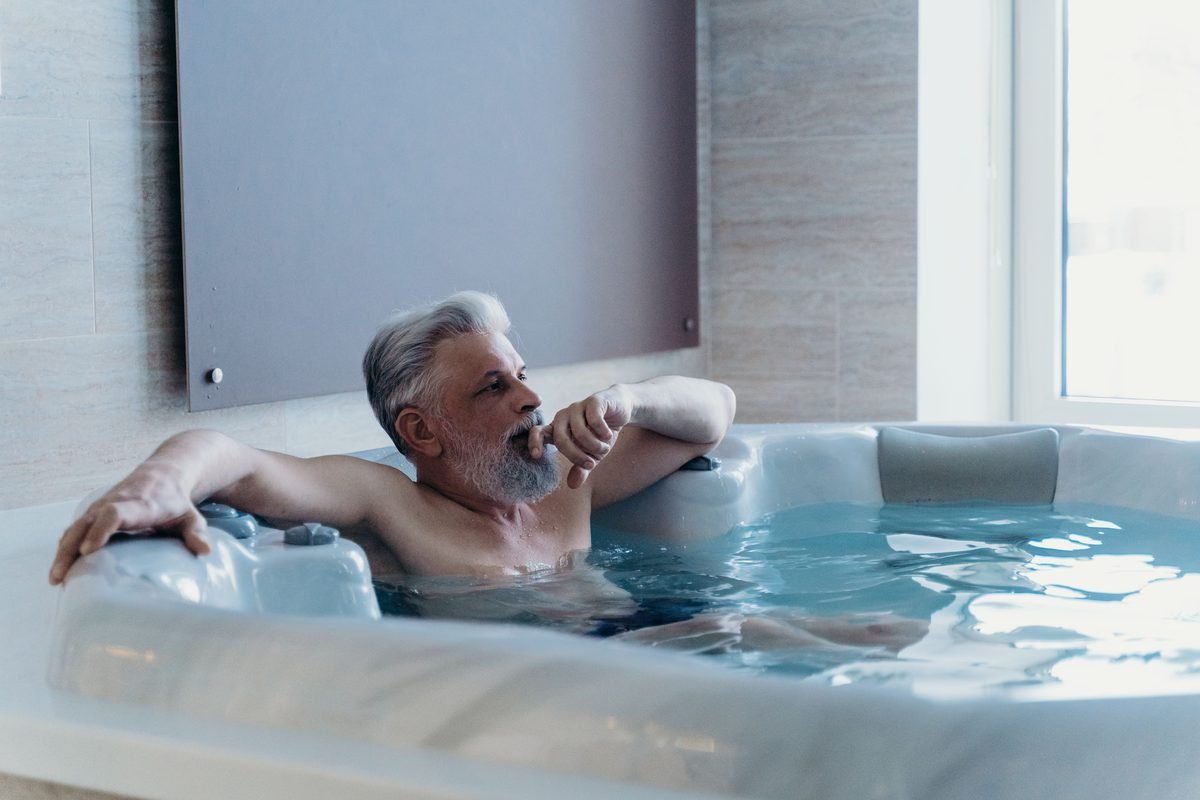 Older man relaxing comfortably inside a modern indoor whirlpool bath