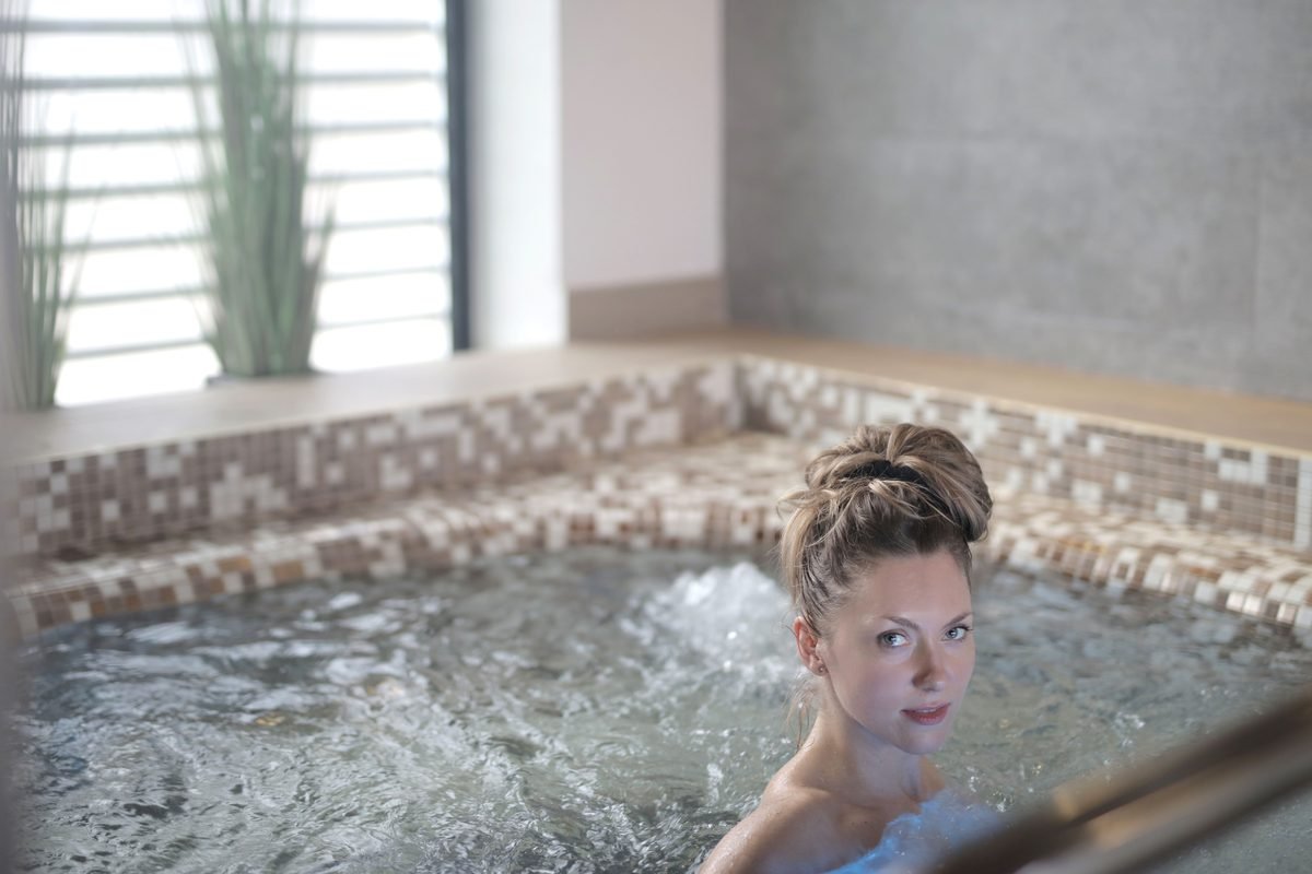 Woman relaxing in a warm indoor spa jacuzzi with soothing water bubbles