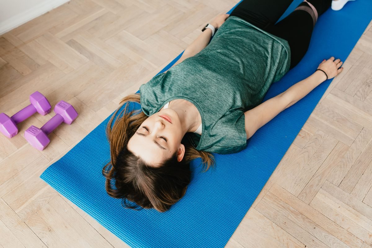 Woman resting comfortably with eyes closed on a blue exercise mat