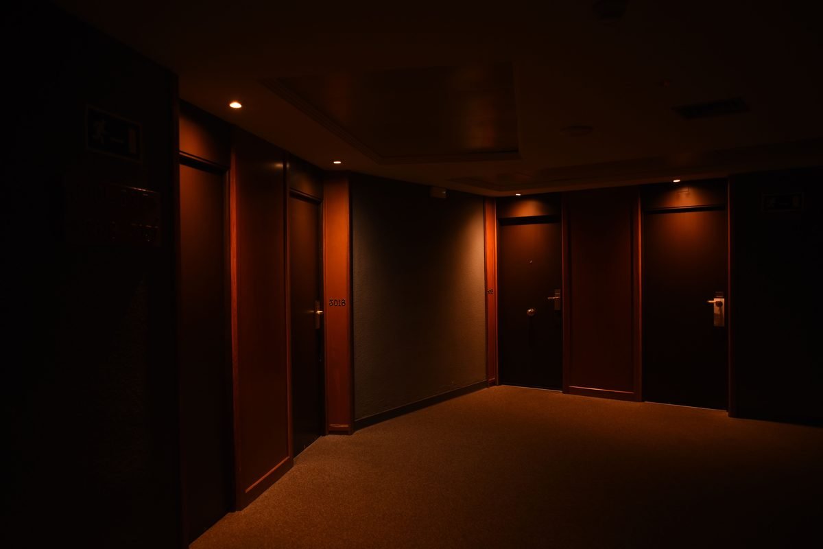 Dimly lit hotel corridor featuring closed wooden doors and soft lighting