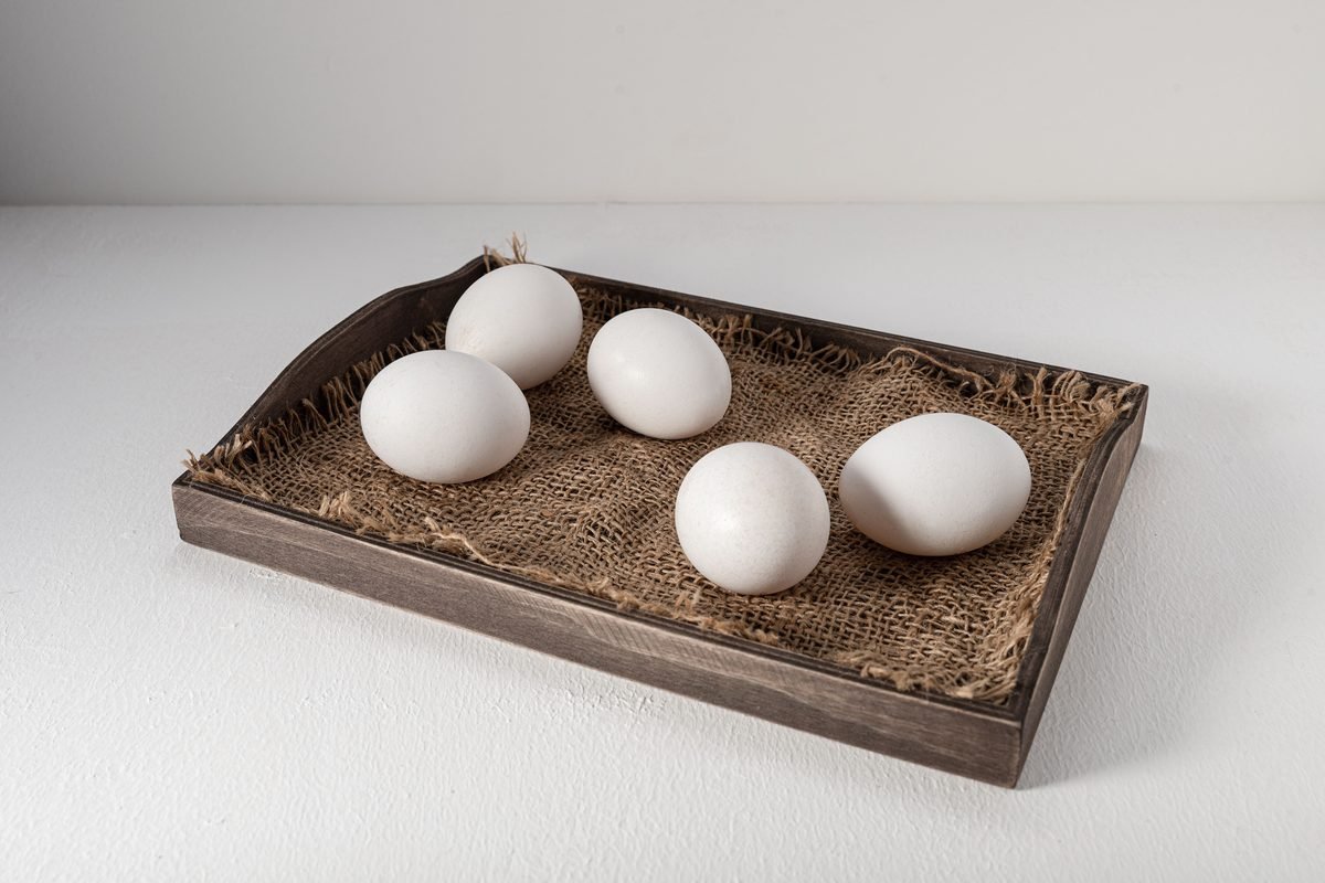 White eggs arranged neatly on a rustic wooden serving tray