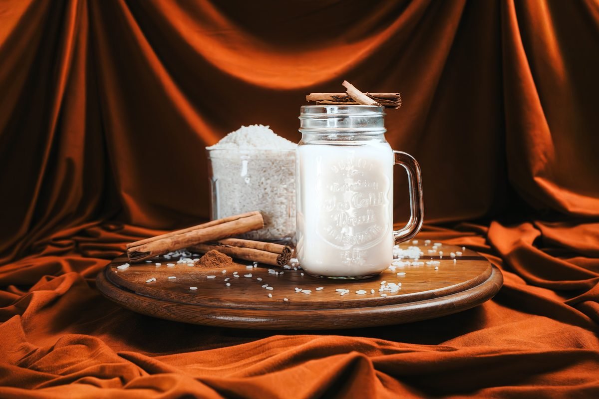 Jar of creamy cinnamon rice milk placed on a rustic wooden board