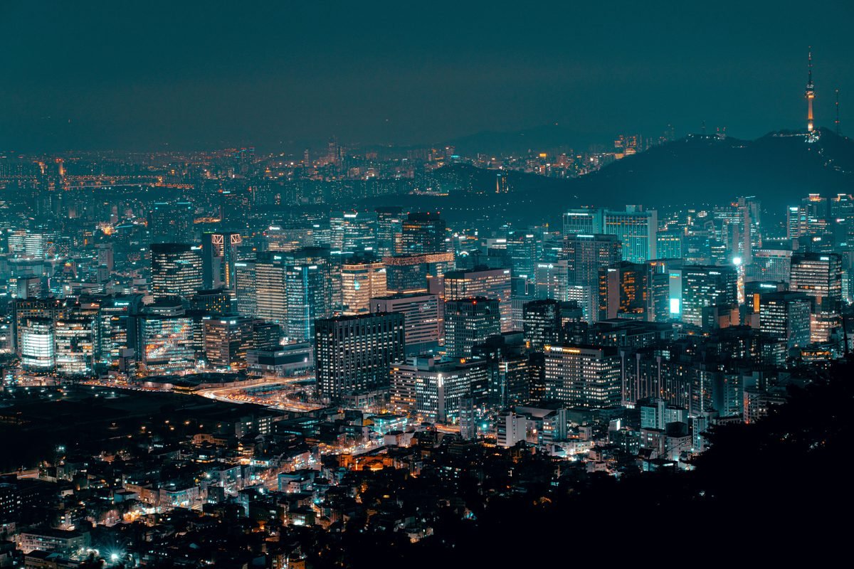 Brightly lit city skyline at night with N Seoul Tower visible.