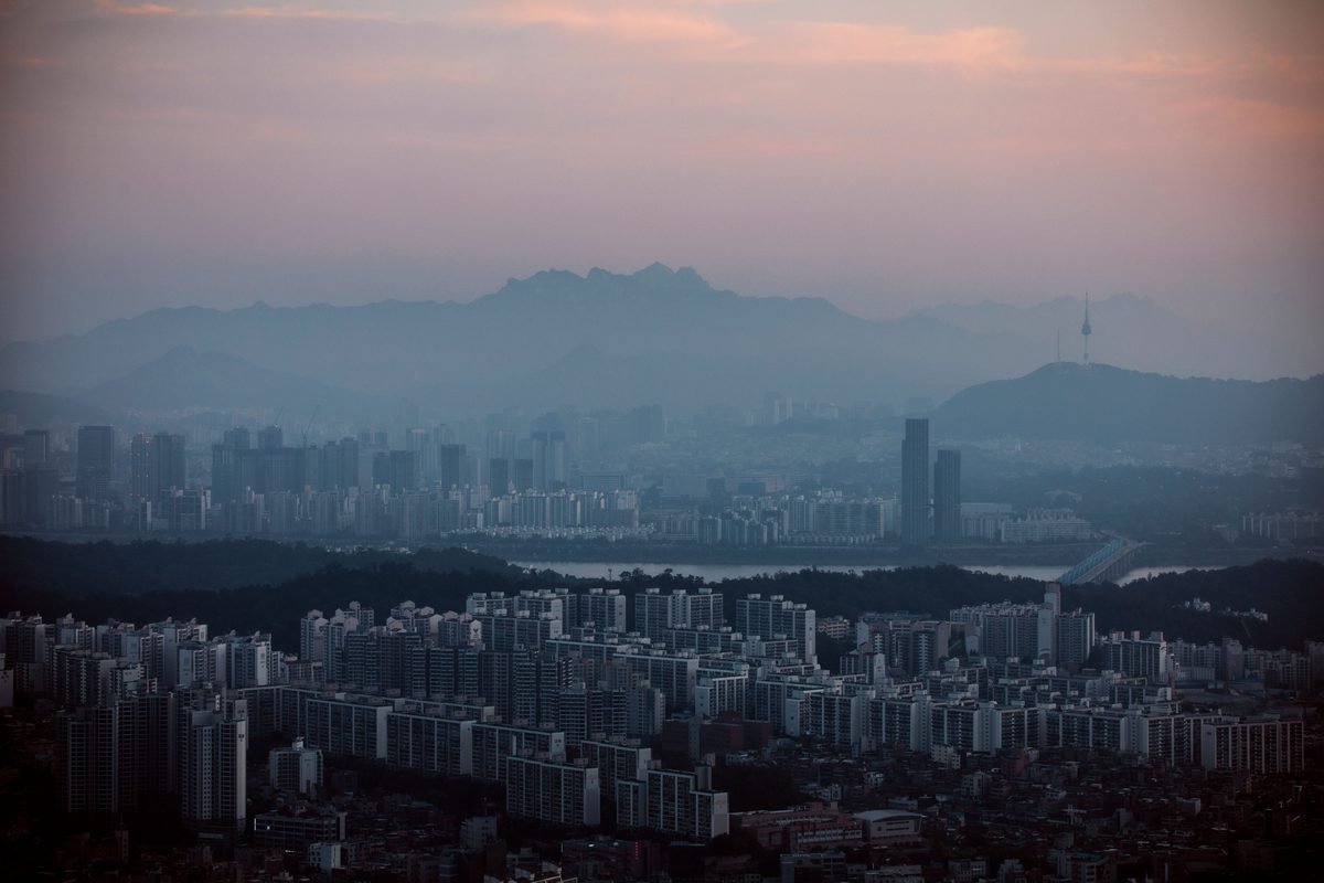 Aerial view of Seoul skyline with misty mountains and Namsan Tower.