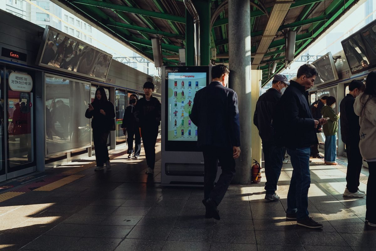 Commuters at a bustling Seoul subway station platform during the day.