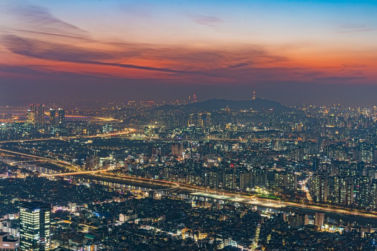 Illuminated Seoul cityscape at dusk with sunset sky.