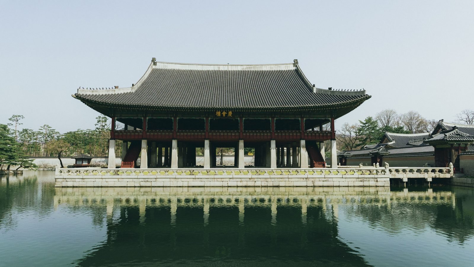 Scenic view of Gyeongbokgung Palace pavilion reflecting in calm water during spring in Seoul, South Korea.