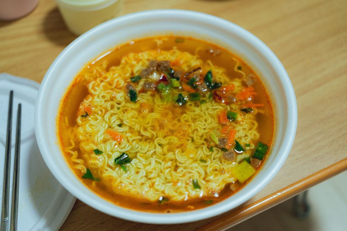 Close-up of a bowl of spicy Korean soup with vegetables on a wooden table in Seoul.