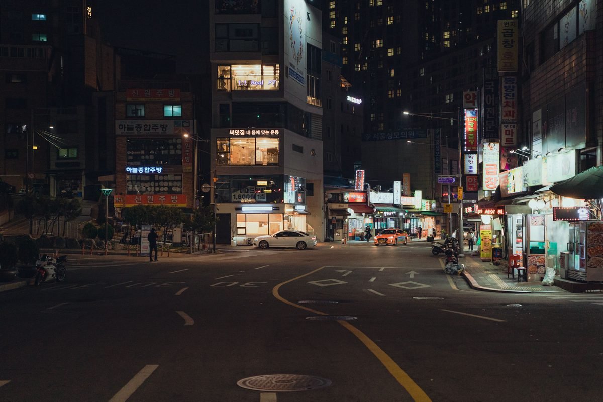 Seoul street at night with glowing neon signs and streetlights.