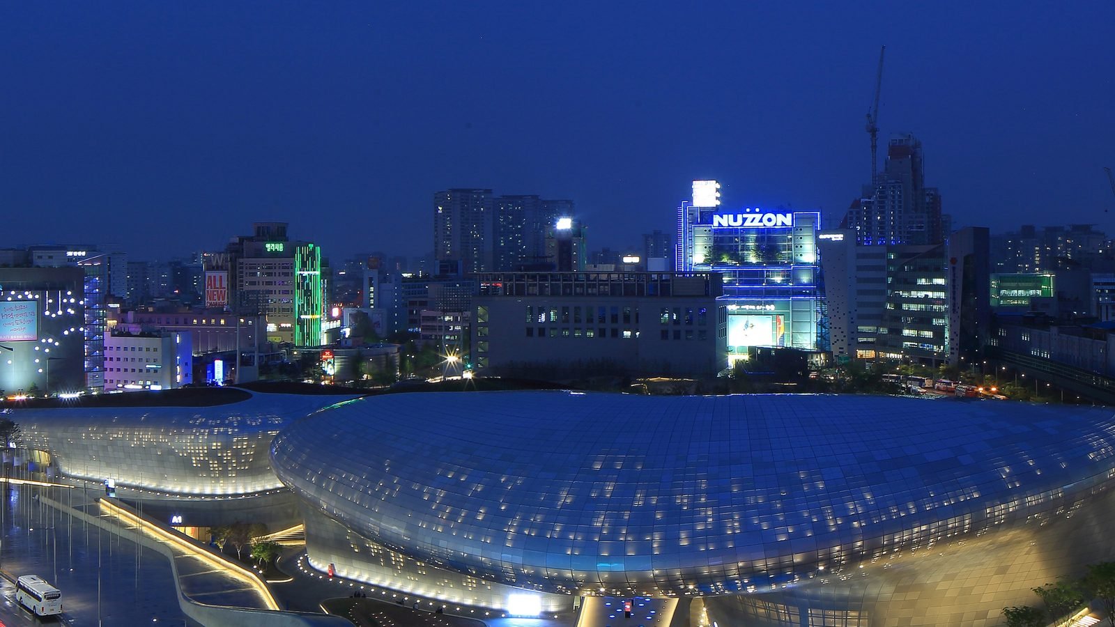 Dongdaemun Design Plaza and surrounding Seoul cityscape illuminated at night.