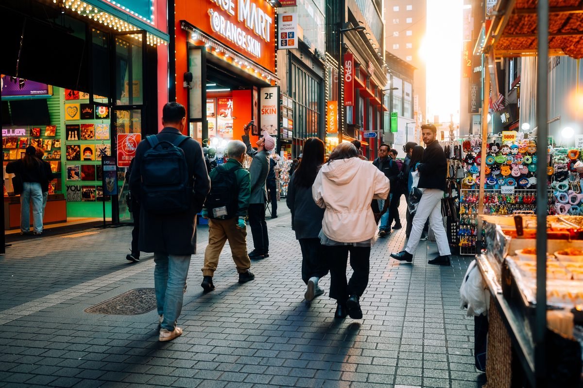 Pedestrians walking down a busy shopping street in Seoul.