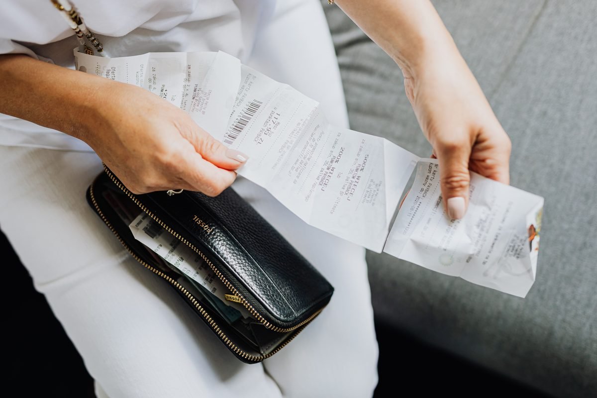 A person managing multiple store receipts pulled from a wallet.