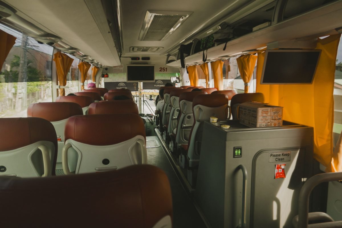 Spacious luxury bus interior with plush seats and monitors.
