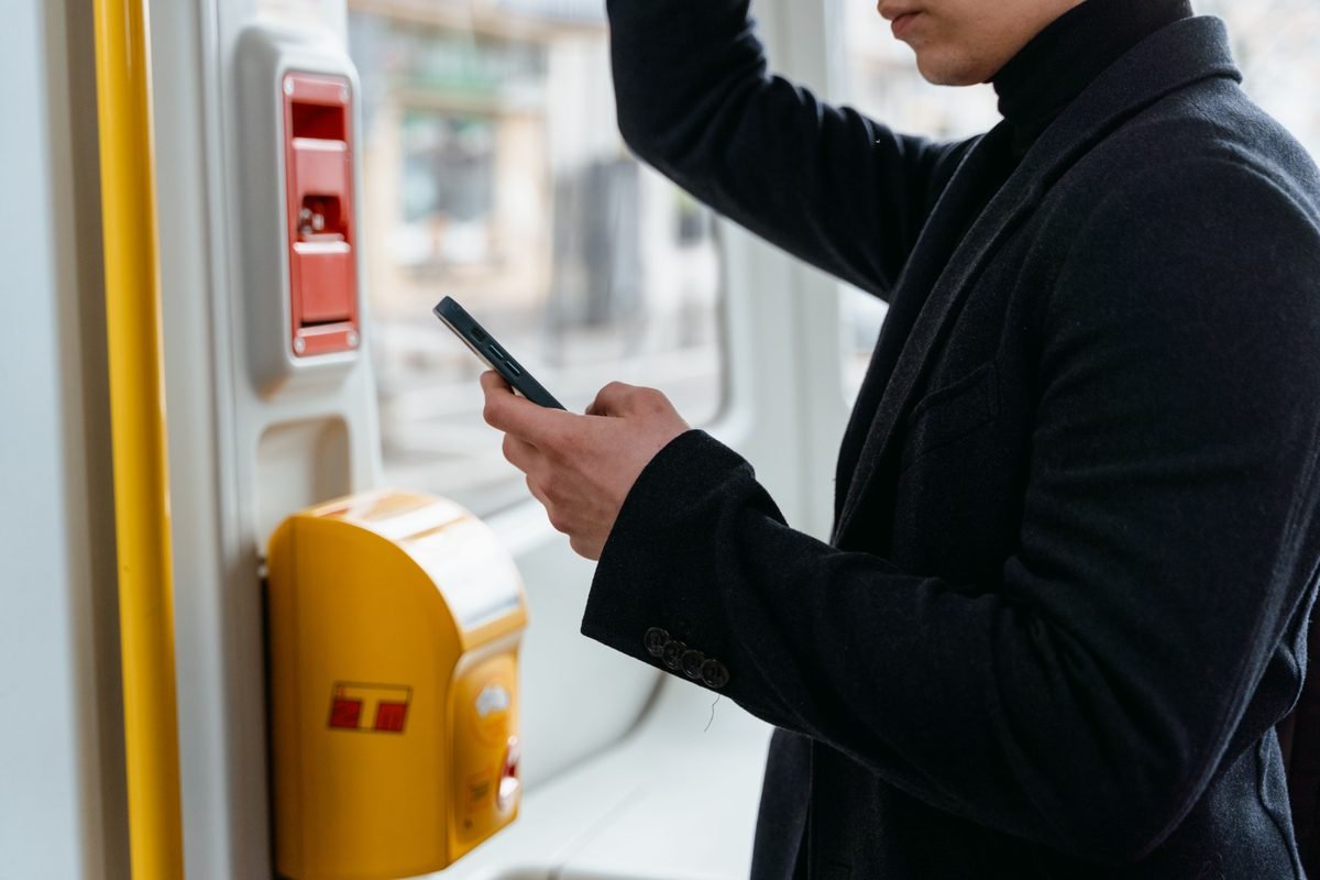 Commuter checking smartphone on public transport.