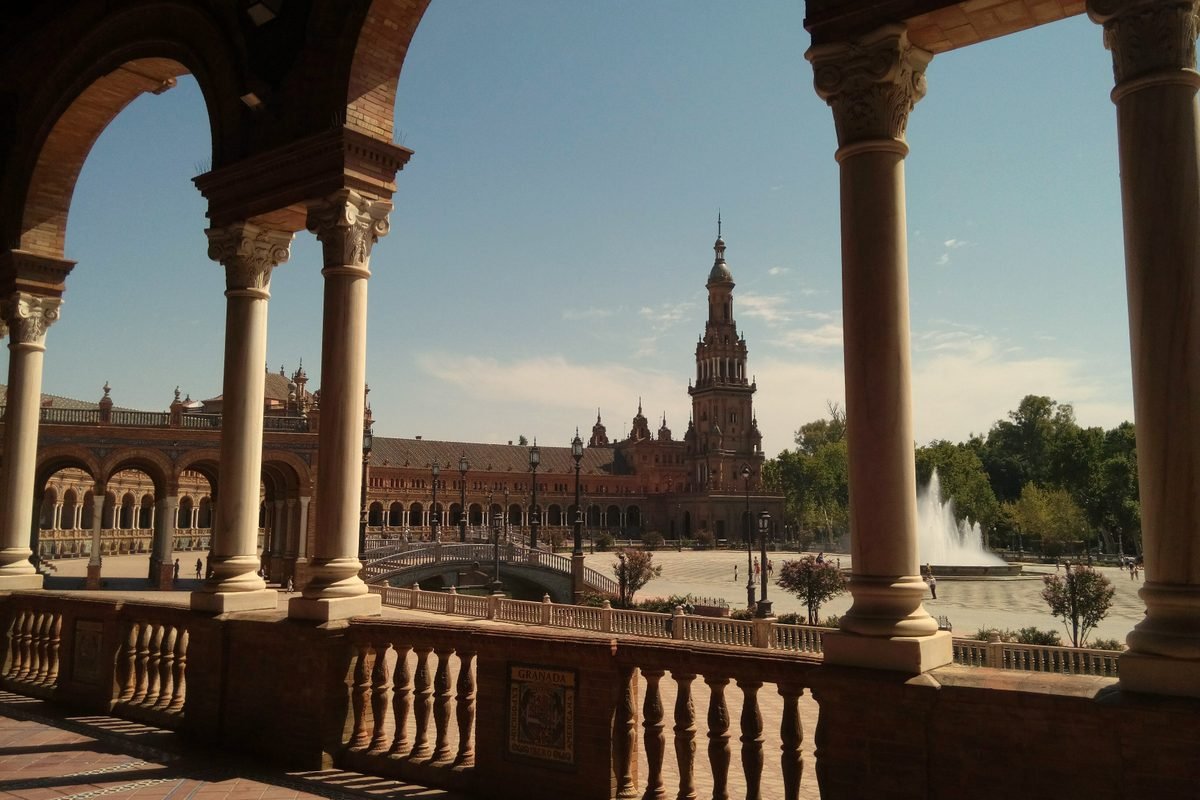 View of Plaza de España framed through shady stone arches.
