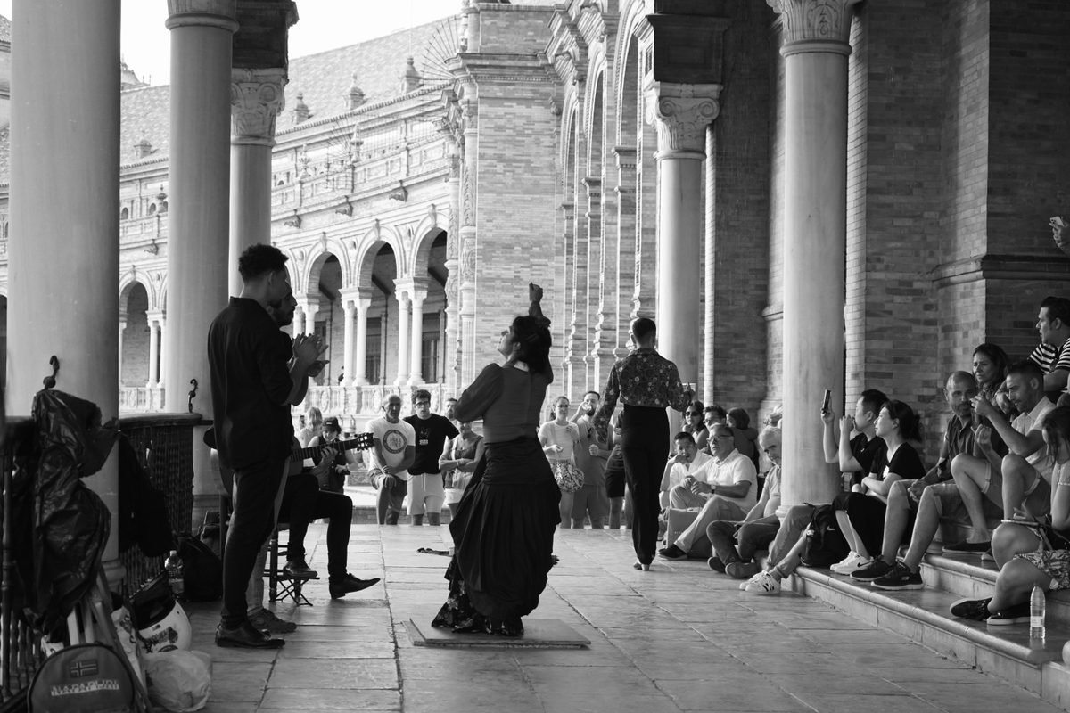 Flamenco dancers performing on a stage in Seville with an audience.