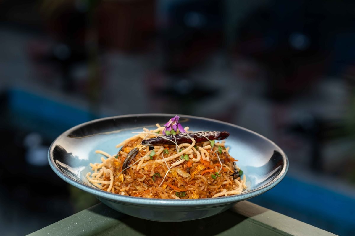 Plate of Asian stir-fried noodles garnished with vegetables and herbs