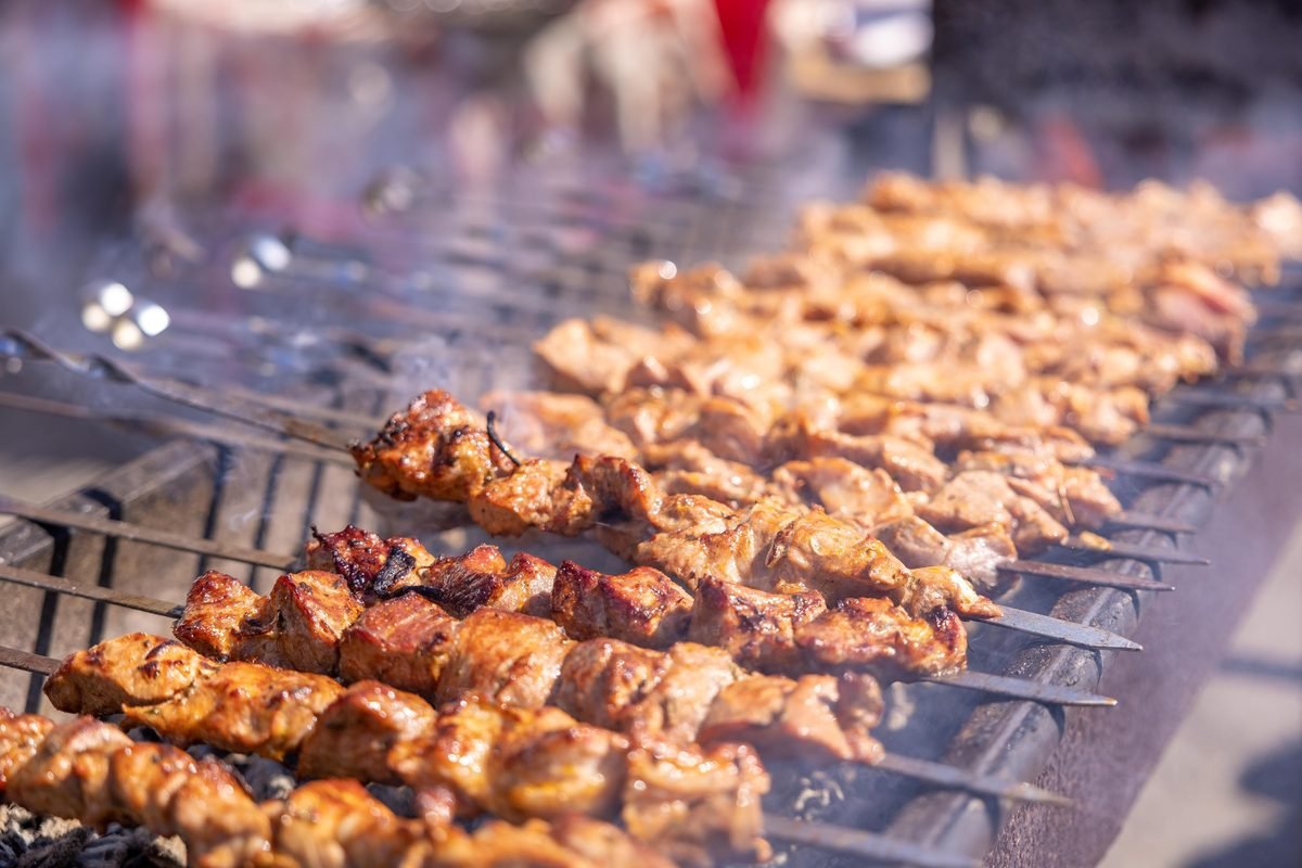 Close-up of sizzling grilled meat skewers on a barbecue grill outdoors