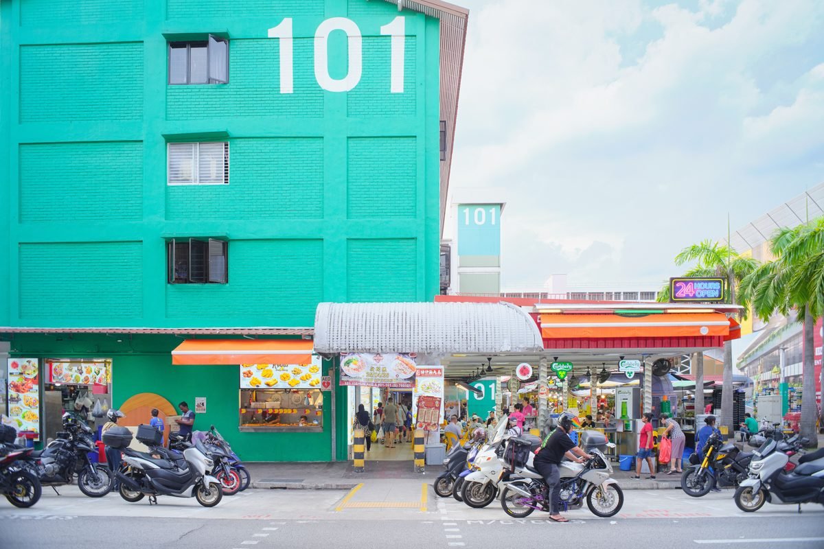 Street view of a market building with scooters and people outdoors