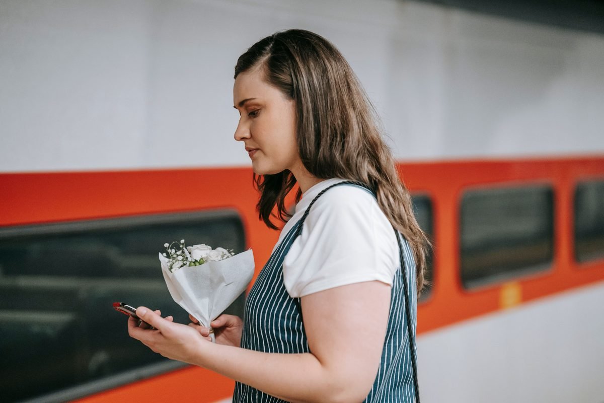 Traveler holding a smartphone near a train station exterior
