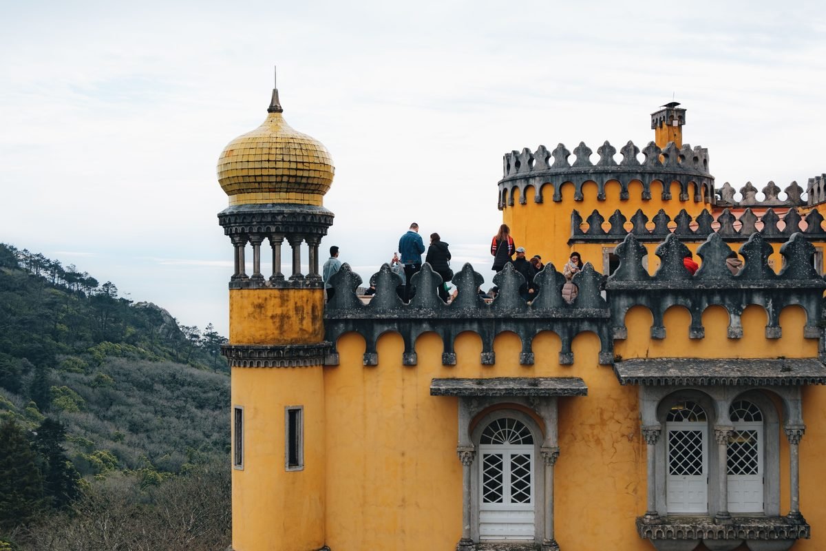 Visitors exploring the historic yellow architecture of Pena Palace