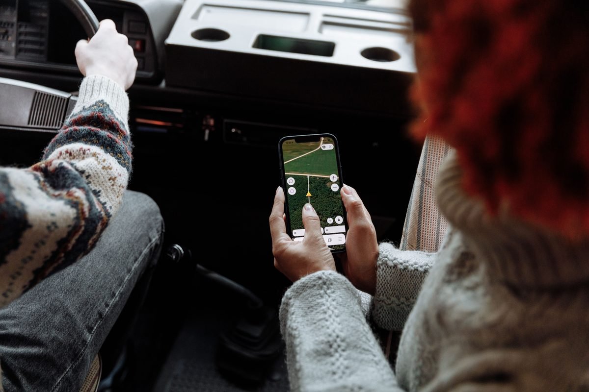 Person holding a smartphone showing a map app inside a vehicle