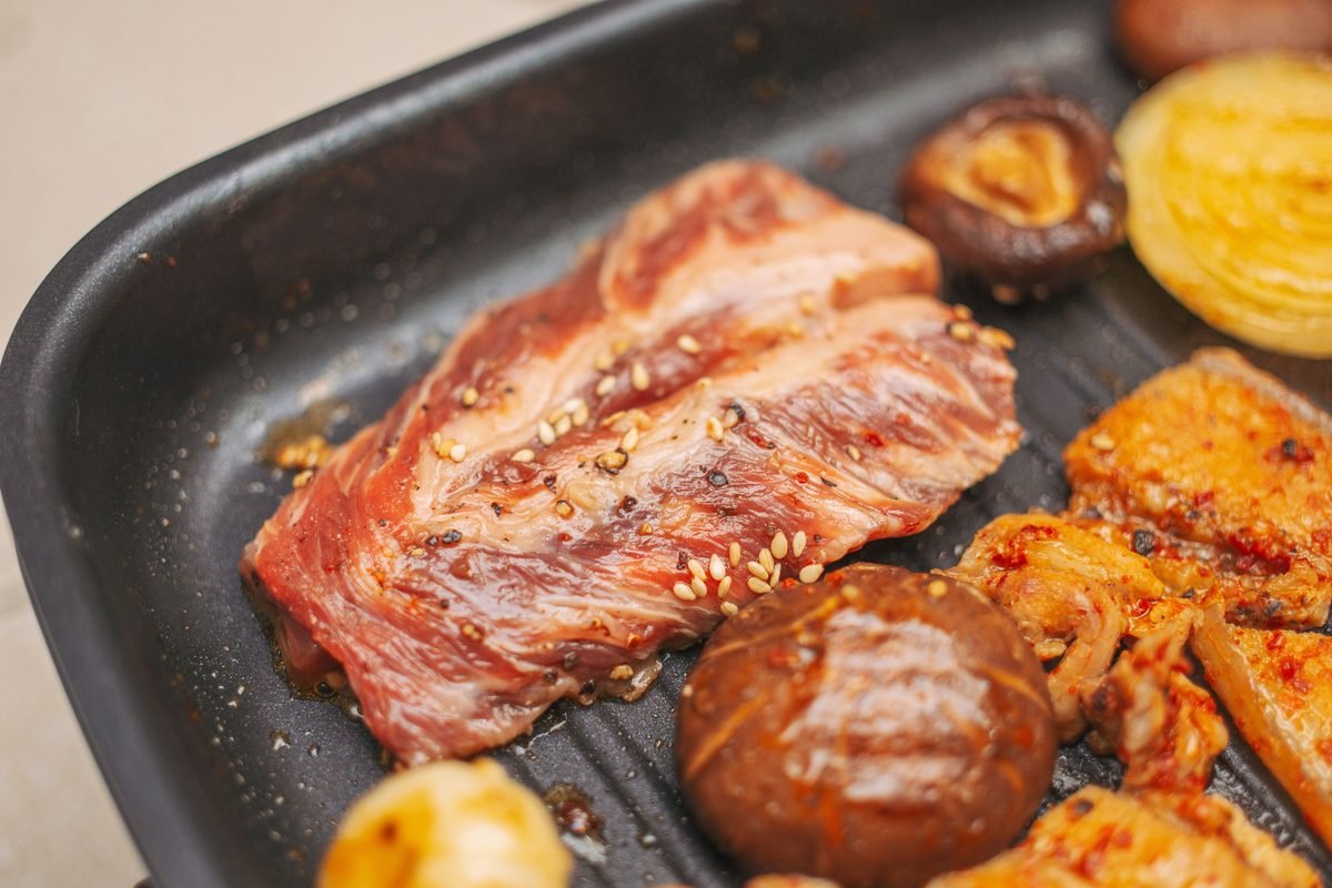 Raw marinated galbi meat and mushrooms on a grill pan