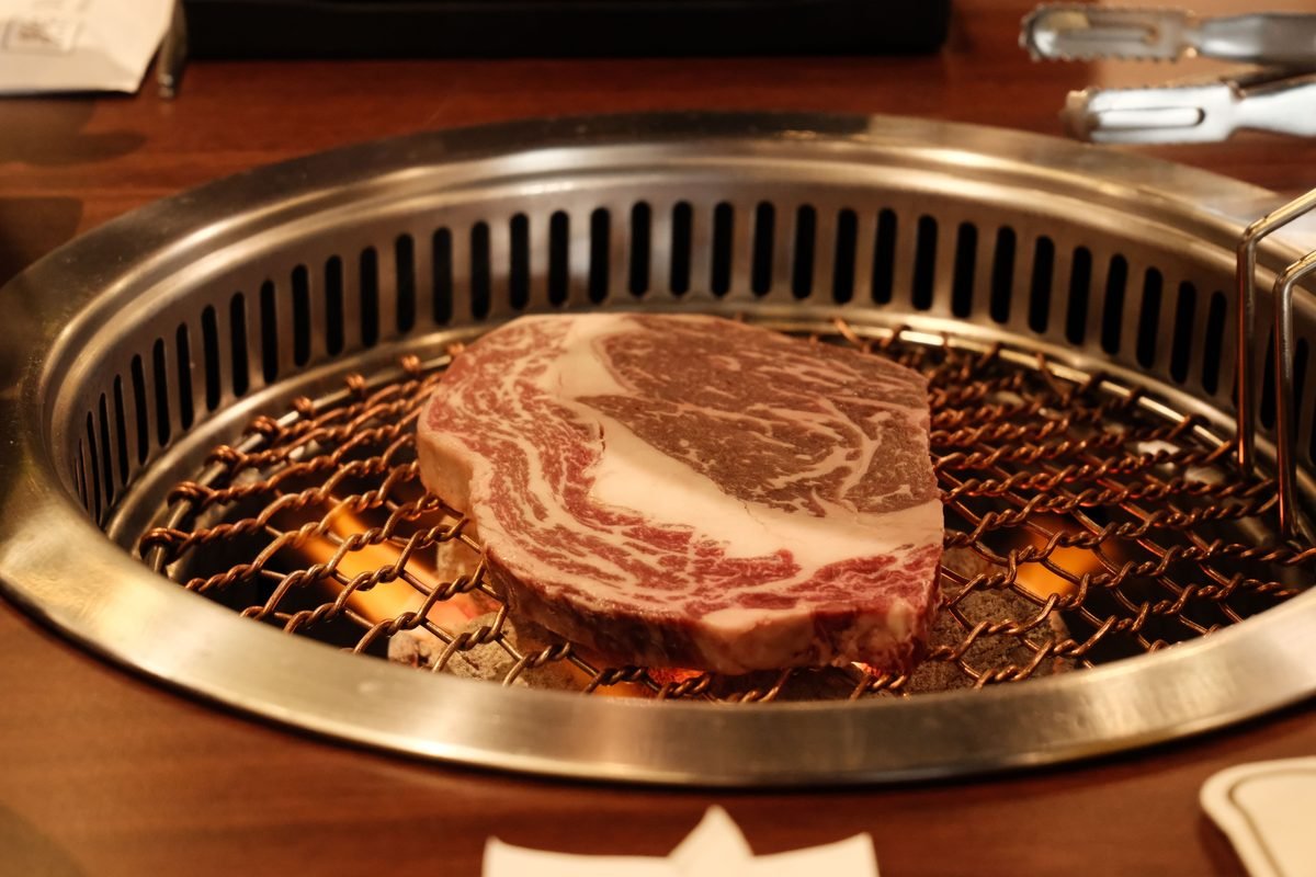 Thick cut of marbled beef steak on a barbecue grill