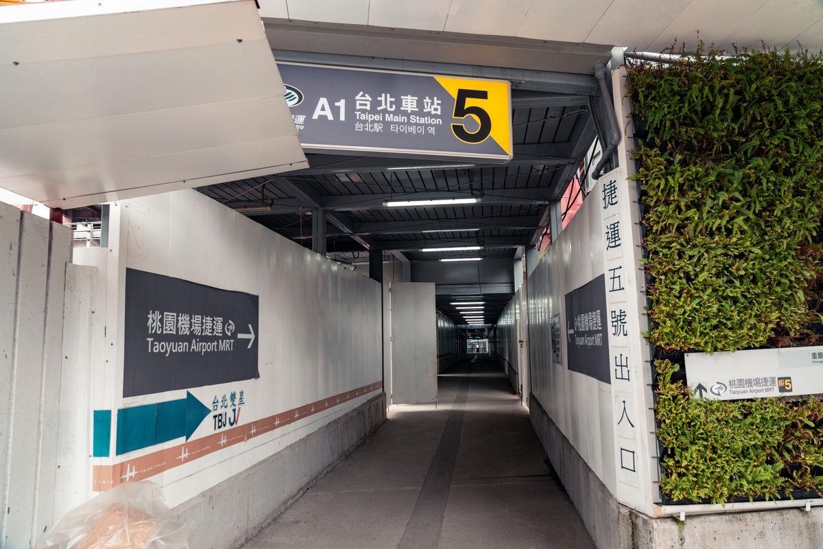 Covered walkway leading to Taipei Main Station Exit 5 with airport MRT signs