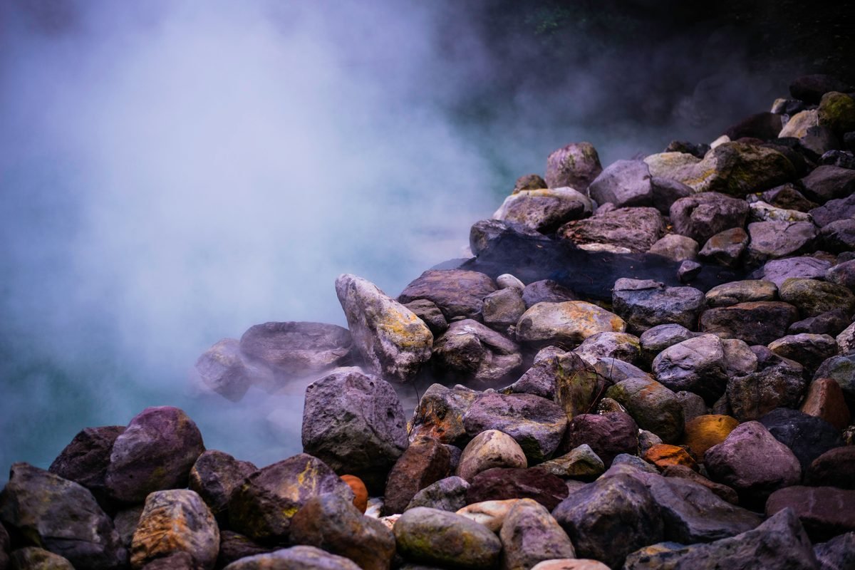 Steaming geothermal hot springs surrounded by colorful boulders
