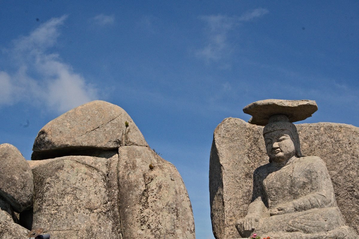 Ancient stone Buddha statues set against a clear blue sky in Daegu