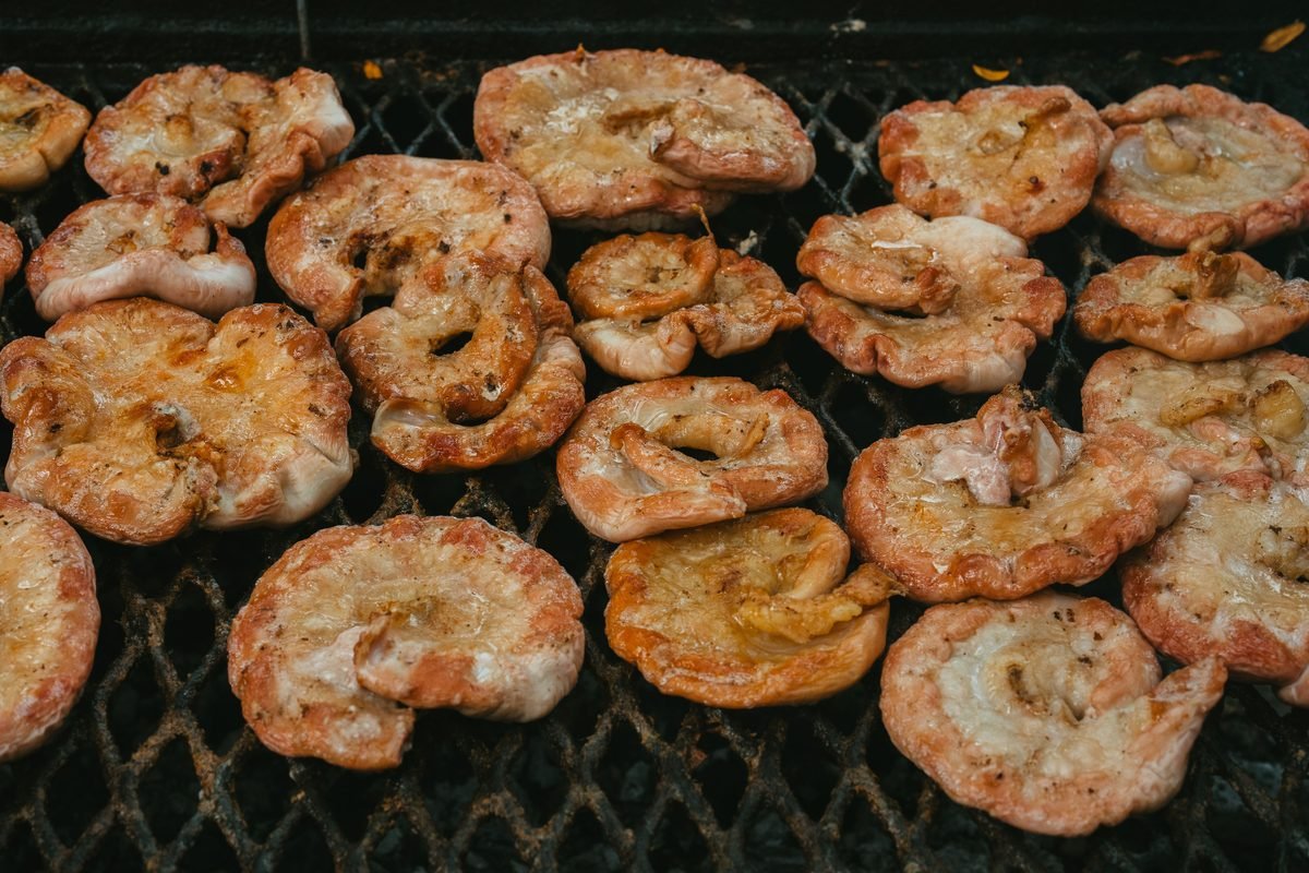 Sizzling grill covered with round slices of seasoned pork intestines over hot coals