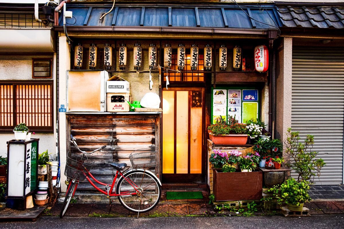Traditional Japanese shopfront with lanterns and a bicycle parked outside.