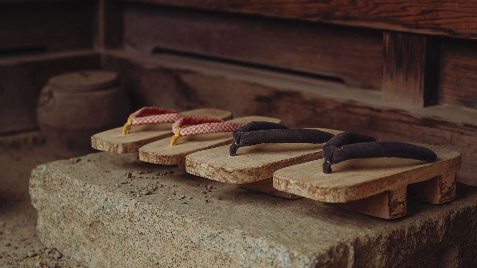 Traditional wooden geta sandals resting on a rustic stone block.