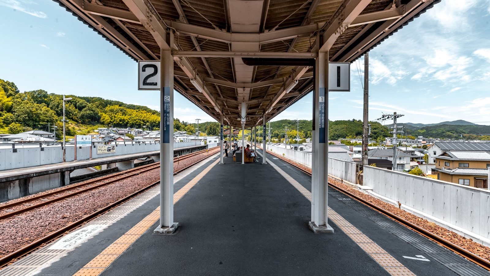View down a quiet covered train platform in the Japanese countryside.