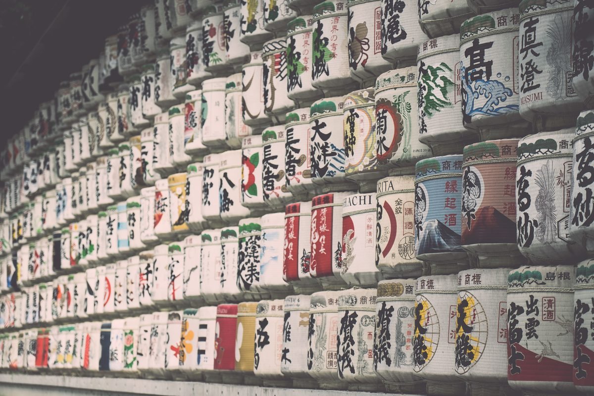 Rows of painted traditional sake barrels stacked closely together.