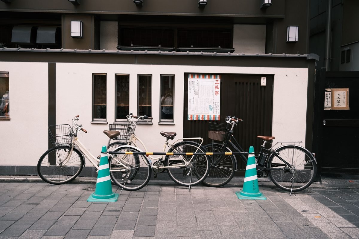 Bicycles parked neatly along a sidewalk in front of a building in Japan.