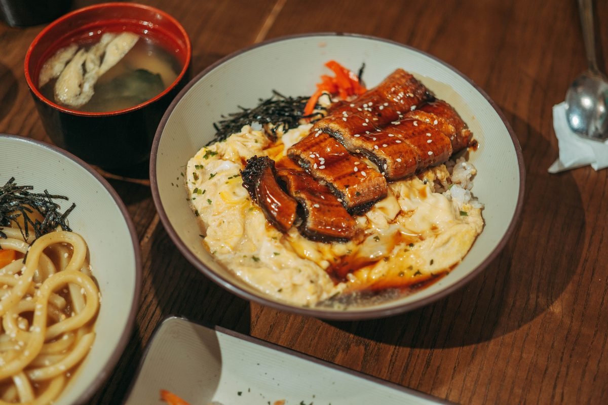 Delicious unagi donburi served in a bowl with miso soup on wood.