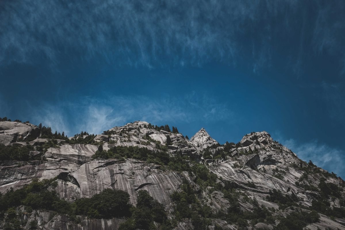 Low angle of rocky slope with uneven peaks and green vegetation