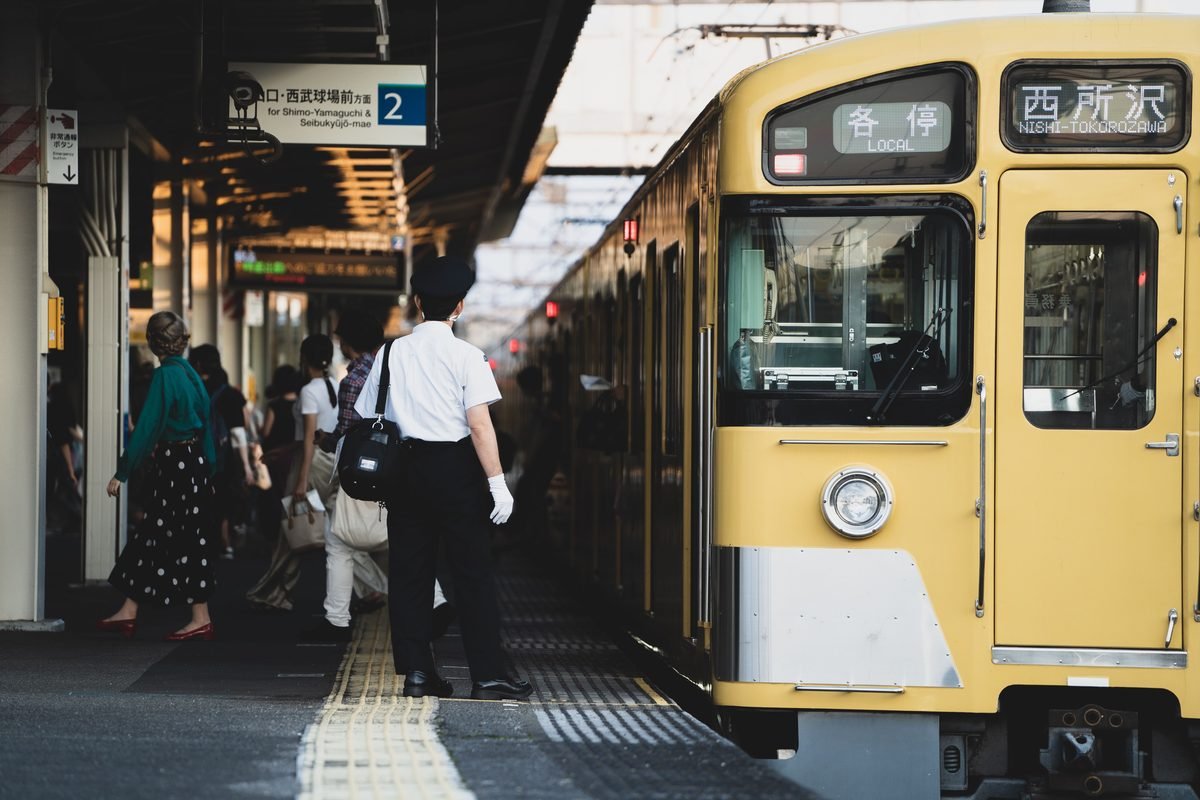 Station staff and passengers on a platform in Japan