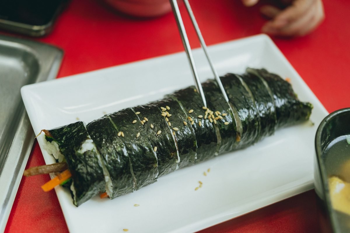 Whole sliced seaweed gimbap roll on a white plate